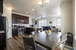Dining space featuring a textured ceiling, crown molding, dark wood-style floors, a chandelier, and ceiling fan