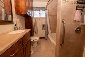 Full bathroom featuring vanity, shower / tub combo with curtain, and light tile patterned flooring