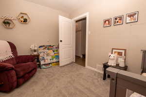 Living area featuring light colored carpet and baseboards