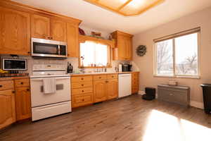 Kitchen with white appliances, backsplash, light wood-style floors, and light countertops