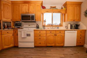 Kitchen featuring white appliances, light countertops, dark wood-style floors, and backsplash