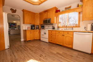 Kitchen with white appliances, light wood-type flooring, and tasteful backsplash