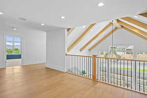 Unfurnished room featuring light wood-style flooring, vaulted ceiling with beams, a chandelier, and a mountain view
