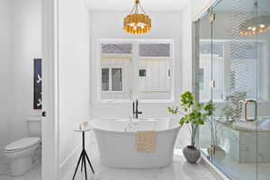 Bathroom featuring a marble finish shower, a freestanding tub, and hanging lights