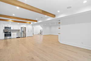 Unfurnished living room with recessed lighting, beam ceiling, and light wood-style floors