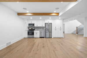Kitchen with white cabinets, stainless steel appliances, recessed lighting, open floor plan, and light countertops