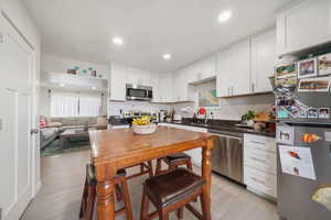 Kitchen with stainless steel appliances, dark stone counters, white cabinetry, light wood finished floors, and recessed lighting