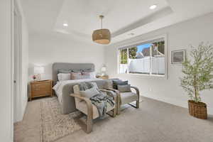 Carpeted bedroom with recessed lighting and a tray ceiling