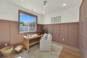 Home office featuring a decorative wall, wainscoting, light wood-style floors, and recessed lighting