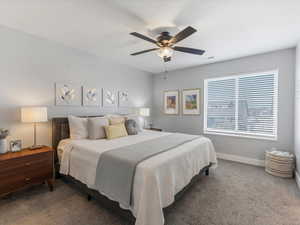 Carpeted bedroom with a ceiling fan and baseboards