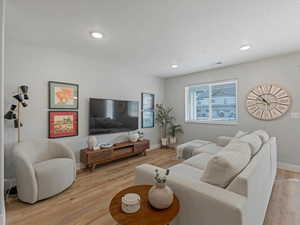 Living room featuring light wood-type flooring, a textured ceiling, and recessed lighting