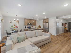 Living area with light wood finished floors and suspended lighting