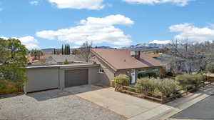 View of front of home with concrete driveway, a mountain view, an attached garage, stucco siding, and a metal roof