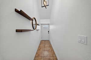 Doorway with a textured wall and tile patterned floors
