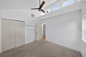 Unfurnished bedroom featuring carpet floors, a closet, a ceiling fan, and a high textured ceiling