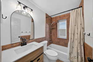 Full bathroom with vanity, tile walls, shower / tub combo with curtain, and wainscoting