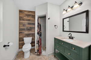 Bathroom featuring vanity, a shower stall, wood walls, and light tile patterned floors