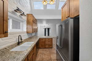 Kitchen featuring wood finish cabinets, high end fridge, a peninsula, light tile patterned floors, and a chandelier