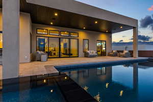 Pool at dusk with outdoor seating, an outdoor pool, and a patio area