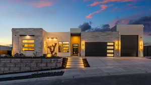 Contemporary house featuring a garage, stone siding, concrete driveway, and stucco siding