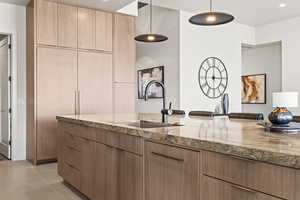 Kitchen with hanging light fixtures, light stone countertops, modern cabinets, light wood finish cabinetry, and light tile patterned floors