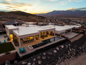 Rear view of property with a mountain view, a patio area, stucco siding, a fenced backyard, and a pool with connected hot tub