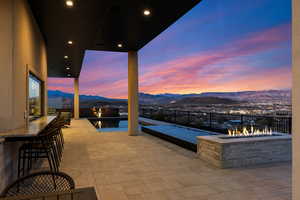 Patio terrace at dusk with a patio, a mountain view, and a pool with connected hot tub