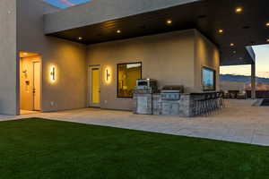 Patio terrace at dusk featuring area for grilling, a patio, a mountain view, and a yard