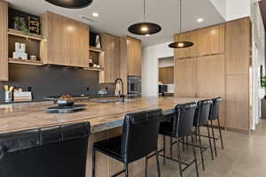 Kitchen featuring pendant lighting, modern cabinets, open shelves, a kitchen bar, and double oven