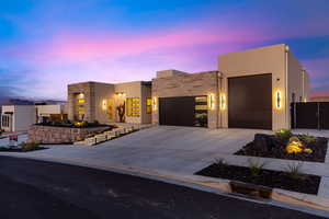 View of front facade with a garage, concrete driveway, stucco siding, and stone siding
