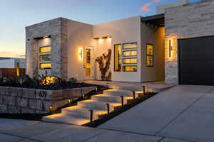 Contemporary home with stone siding, stucco siding, concrete driveway, and an attached garage