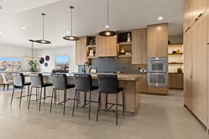 Kitchen featuring hanging light fixtures, open shelves, a breakfast bar, modern cabinets, and a large island