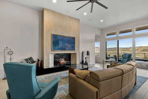 Living room featuring a mountain view, a large fireplace, ceiling fan, recessed lighting, and a high ceiling