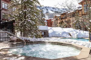 Snow covered pool with a community hot tub and a mountain view