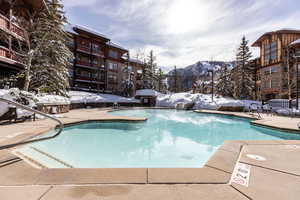 Snow covered pool with a community pool, a patio area, and a mountain view