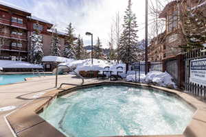 Snow covered pool featuring a community hot tub, a community pool, and a patio area