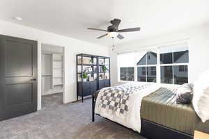 Bedroom featuring a walk in closet, carpet floors, and a ceiling fan