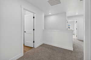 Corridor with light carpet and recessed lighting