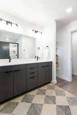 Full bath with double vanity, a shower stall, and light wood-style flooring