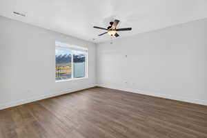 Spare room featuring dark wood-type flooring and a ceiling fan