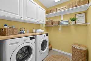 Laundry area with cabinet space, washing machine and clothes dryer, and light tile patterned floors