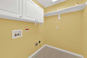 Washroom with hookup for a washing machine, cabinet space, hookup for a gas dryer, electric dryer hookup, and light tile patterned floors