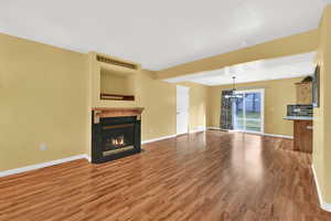 Unfurnished living room with a chandelier, a premium fireplace, and light wood-style flooring