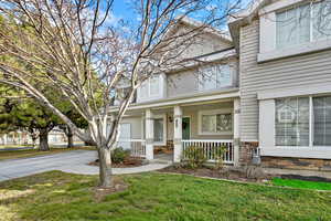 View of front of house with stone siding, a porch, a front yard, and driveway