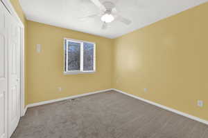 Unfurnished bedroom with a closet, carpet floors, a ceiling fan, and a textured ceiling