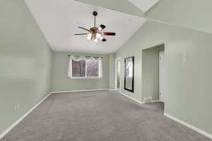Carpeted empty room with lofted ceiling and a ceiling fan