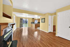 Unfurnished living room with light wood-style flooring, a warm lit fireplace, and a chandelier