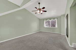 Carpeted empty room featuring lofted ceiling and a ceiling fan