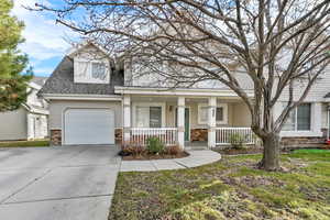 View of front of property with stone siding, a shingled roof, covered porch, concrete driveway, and a garage