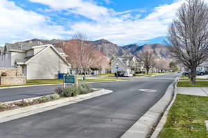 View of asphalt road featuring a residential view, curbs, and a mountain view